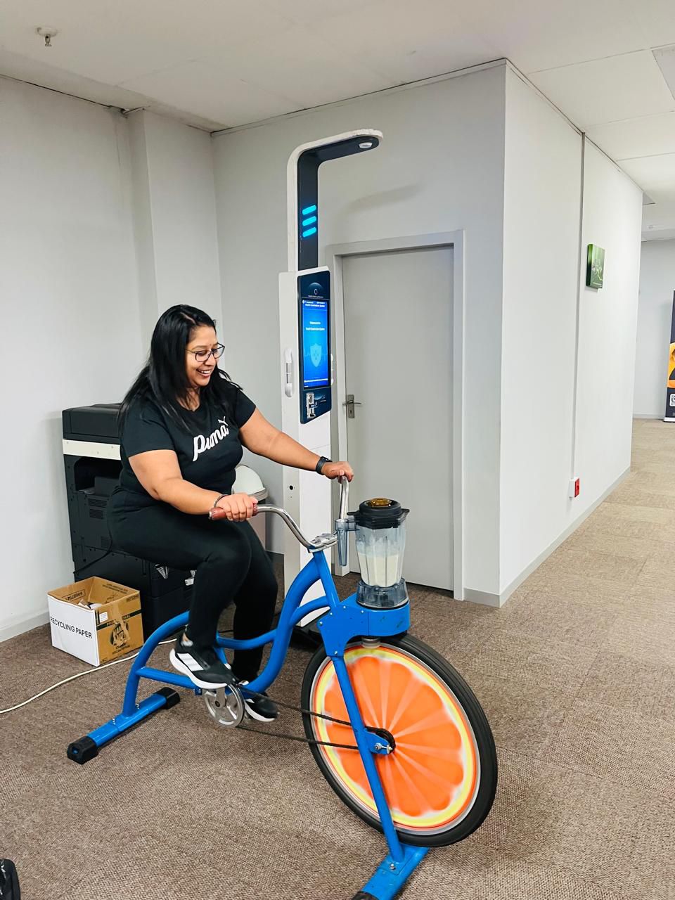 Rider pedalling a blue smoothie bike with orange-slice wheel at an event